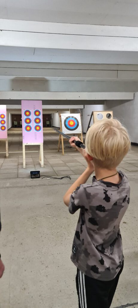 Kind schießt mit dem Blasrohr auf eine Zielscheibe